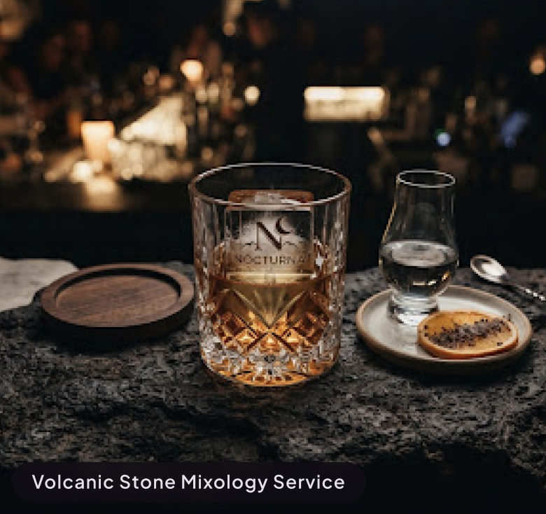 Top-down elegant cocktail display at a midnight bar in Mexico City, crystal glassware with clear ice on dark volcanic rock surface